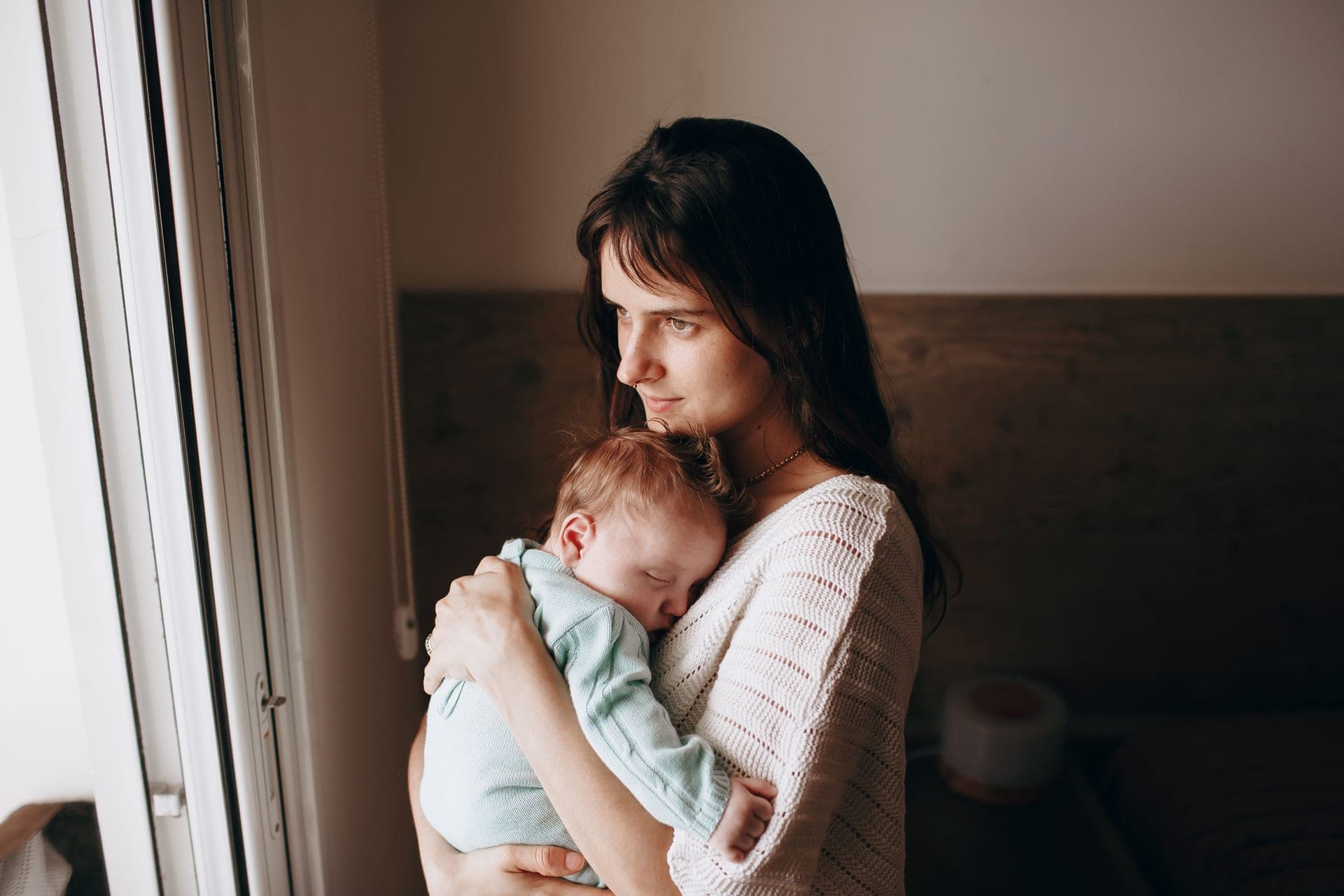 A parent and baby in a calm, warmly lit nursery at home
