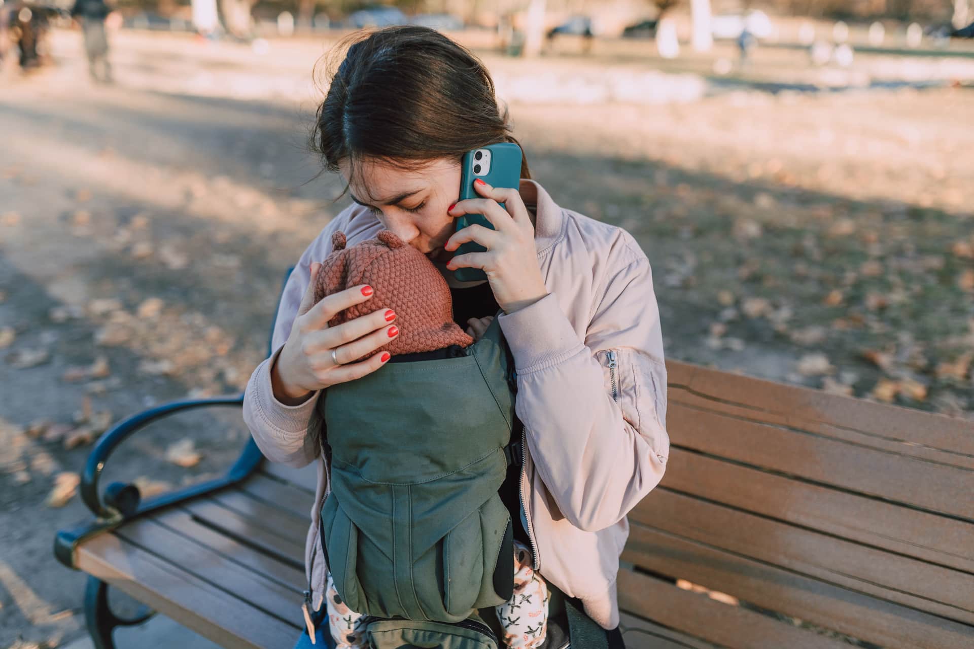A parent walking outdoors while wearing a baby in a carrier